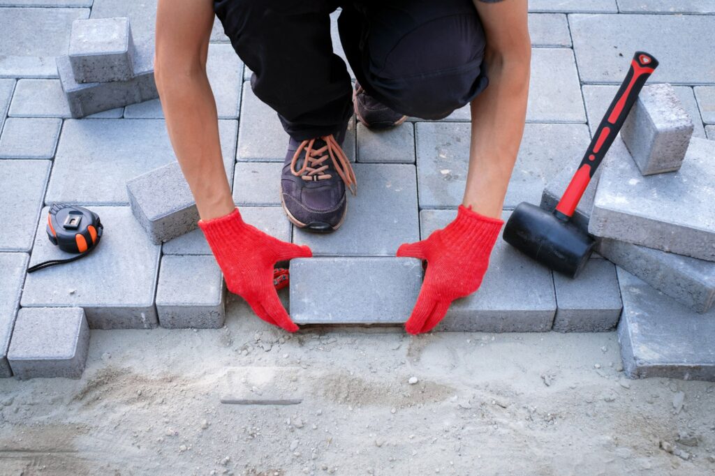 The master in yellow gloves lays paving stones